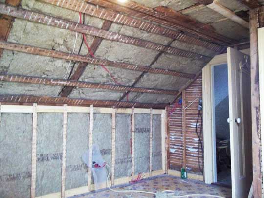 Interior view of attic space of Cape Cod home with new insulation in knee wall and ceiling