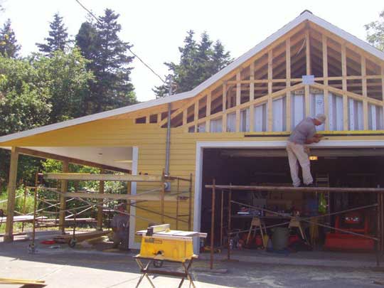 Yellow siding installed over framing around Quonset hut, and on car port addition on the side