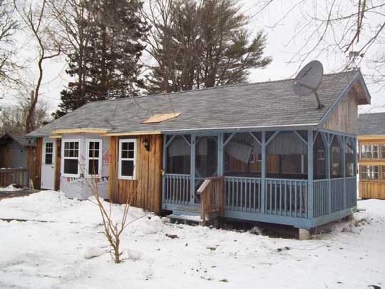 New roof over the bay window added to the heritage Caledonia split log siding cottage.
